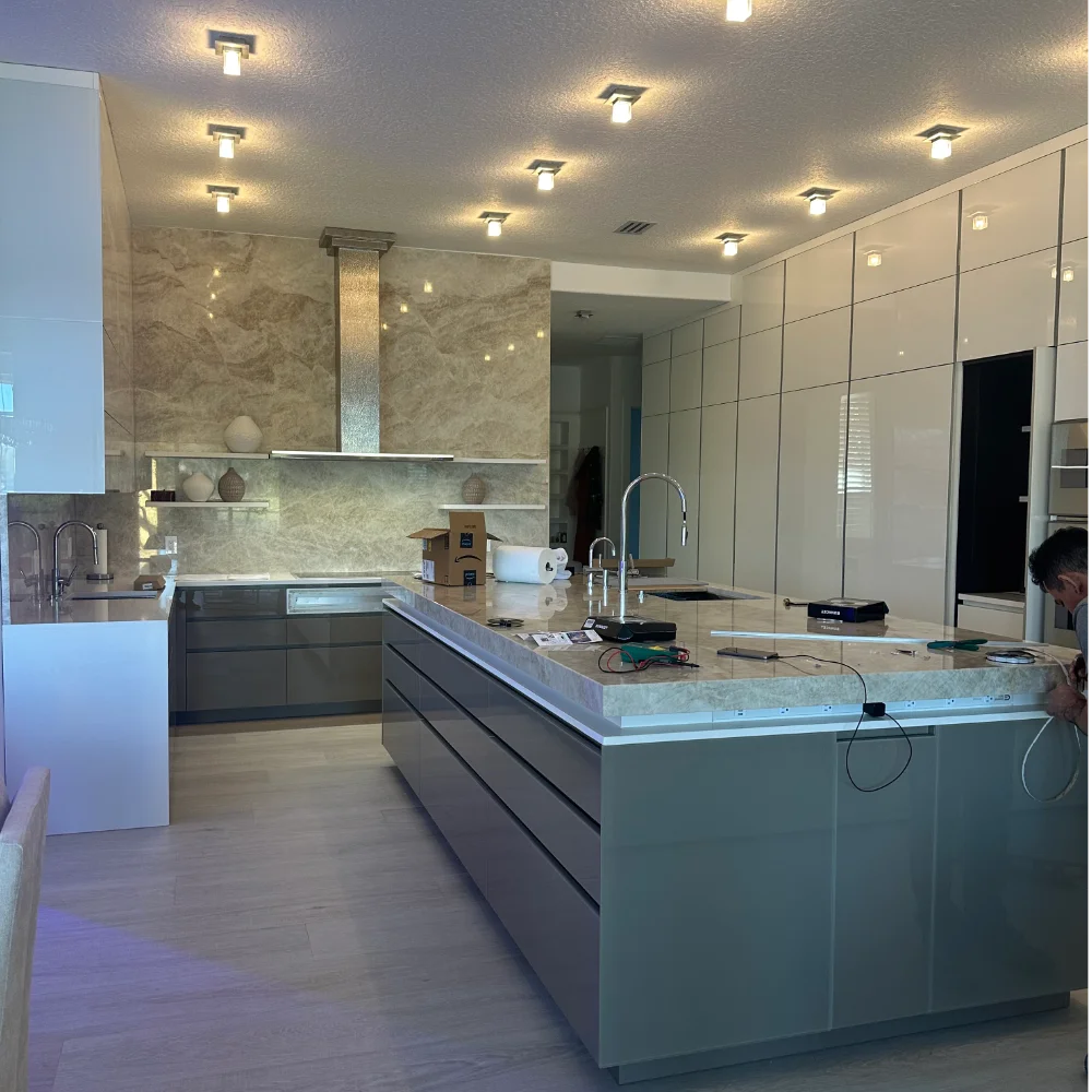 Complete open-concept interior remodeling in Jacksonville, FL, featuring a large center marble island with elegant silver plumbing that serves as a table, looking into a modern living space.